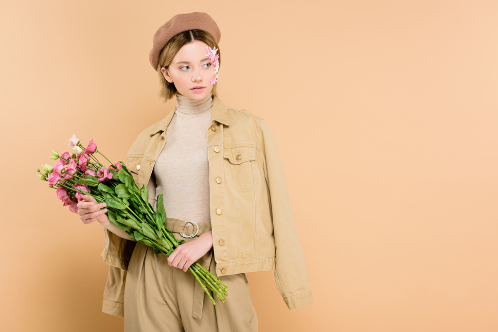 donna alla moda che tiene bouquet con fiori isolati sul beige
  - Foto, immagini