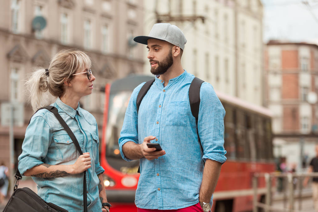 Young woman and man talking in the city street, tram in the background.  - Photo, Image