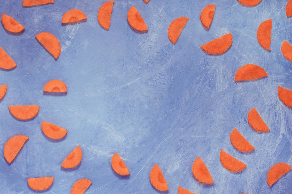 Нарезанные половинки оранжевой моркови на ярко-голубом фоне. Текстура. Концепция дизайна, пространство для копирования
 - Фото, изображение