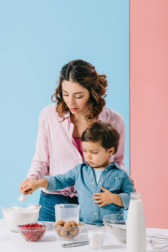 szép anya, az aranyos kis fia, főzés a konyhában bicolor háttérrel együtt - Fotó, kép