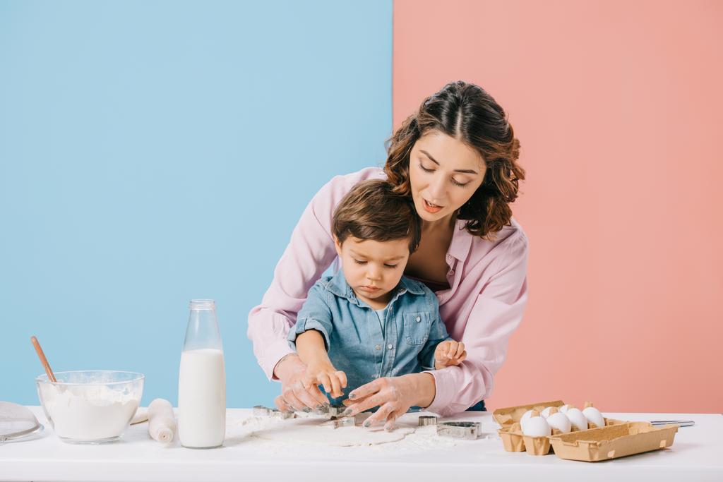 szép anya és kis fia vágási számmal tésztát bicolor háttérrel együtt  - Fotó, kép