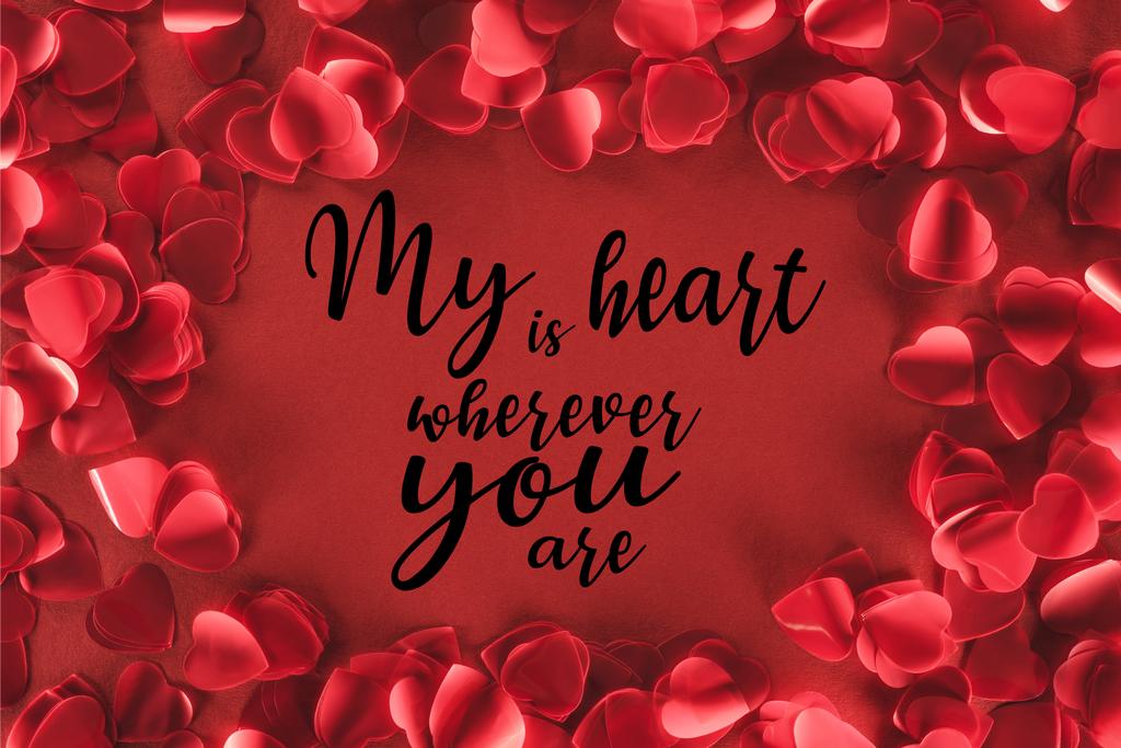 vista superior de pétalos decorativos en forma de corazón sobre fondo rojo con letras "mi corazón está donde quiera que estés", concepto de día de San Valentín
  - Foto, Imagen