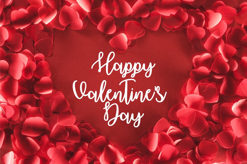 vista superior de hermoso marco en forma de corazón de pétalos decorativos sobre fondo rojo con letras de "Feliz día de San Valentín"
 - Foto, imagen