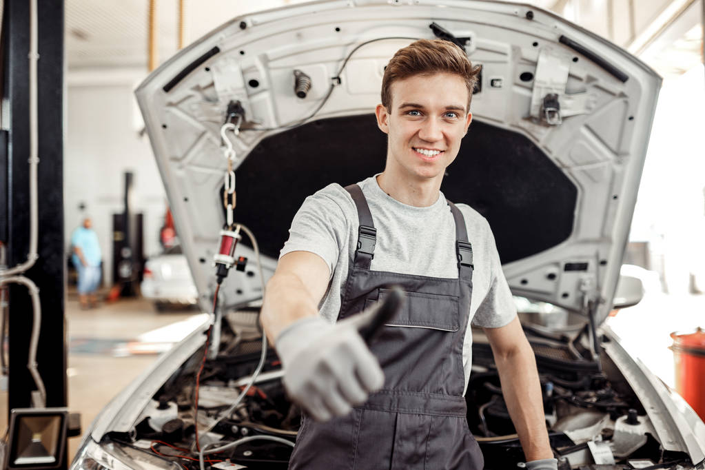 Un joven guapo está en su trabajo: servicio de reparación de coches
 - Foto, Imagen