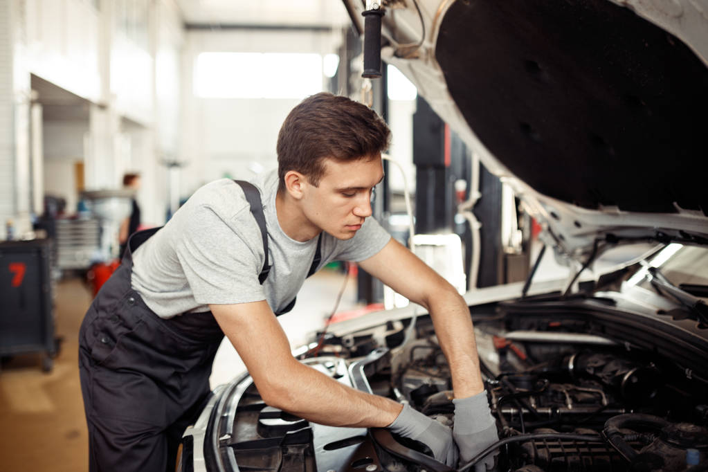 Een gekwalificeerde automachanic is het repareren van een auto op een car-service - Foto, afbeelding
