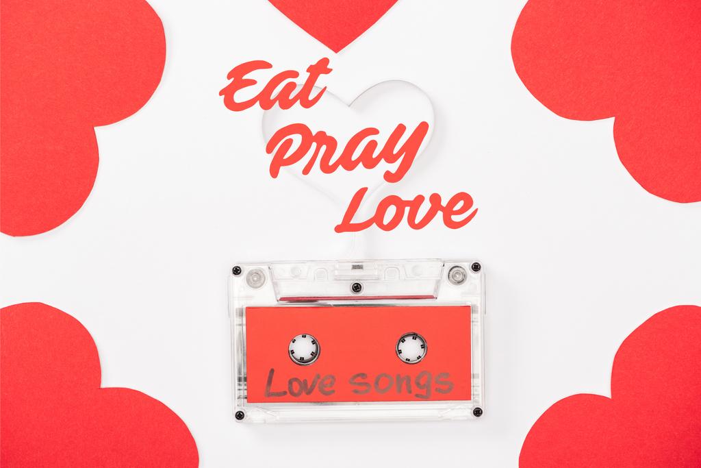horní pohled na audiokazetu s "milostné písně" nápisy a srdce ve tvaru karty izolované na bílém, st Valentýn koncept "jíst, modlit se, láska" nápisy - Fotografie, Obrázek
