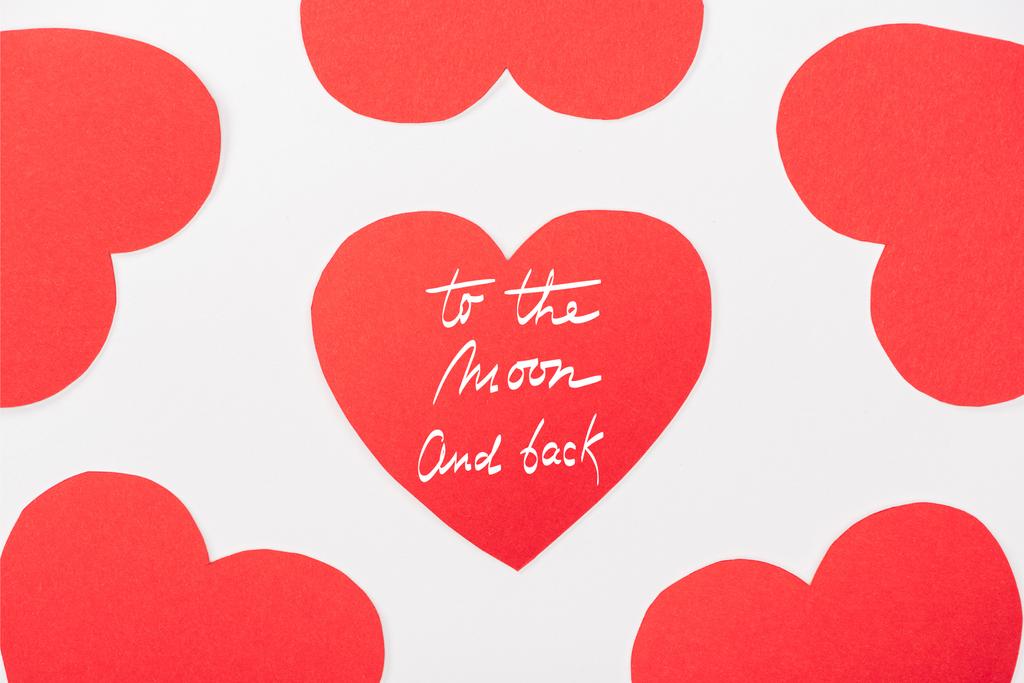 background with heart shaped paper cards isolated on white, st valentines day concept with "to the moon and back" lettering - Photo, Image