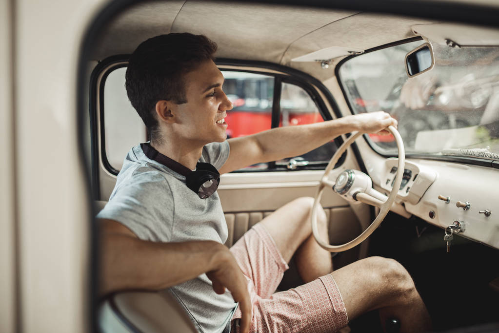 Молодой и привлекательный мужчина водит винтажный автомобиль
 - Фото, изображение