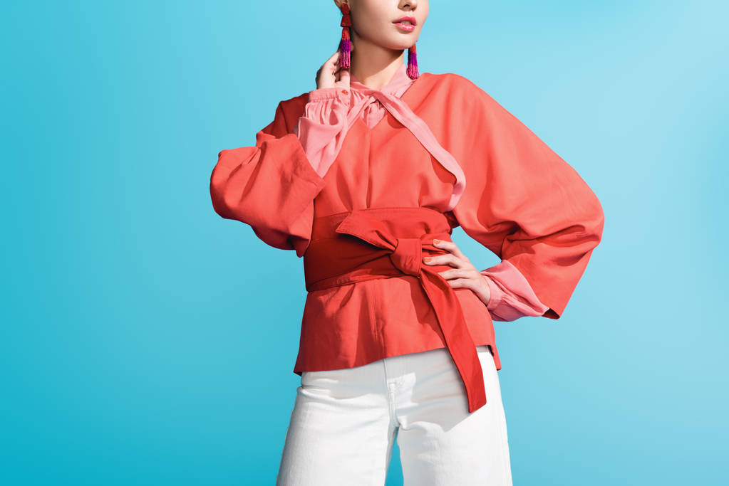 cropped view of fashionable girl posing in trendy living coral clothing isolated on blue - Photo, Image