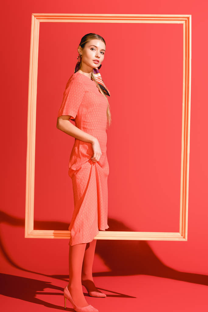 hermosa chica elegante en vestido posando con gran marco en coral vivo. Pantone color del año 2019 concepto
 - Foto, Imagen