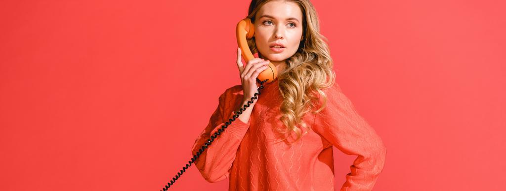 サンゴに分離されたレトロなダイヤル式電話で魅力的な女性。2019 年概念の Pantone カラー - 写真・画像