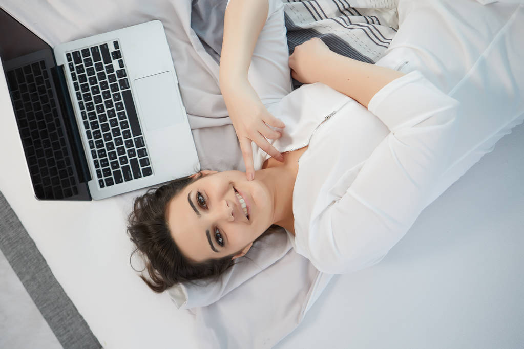 жінка використовує ноутбук на ліжку
  - Фото, зображення