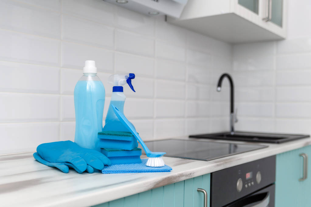 Un conjunto de productos de limpieza azul y herramientas para la limpieza está en la mesa de la cocina
. - Foto, Imagen