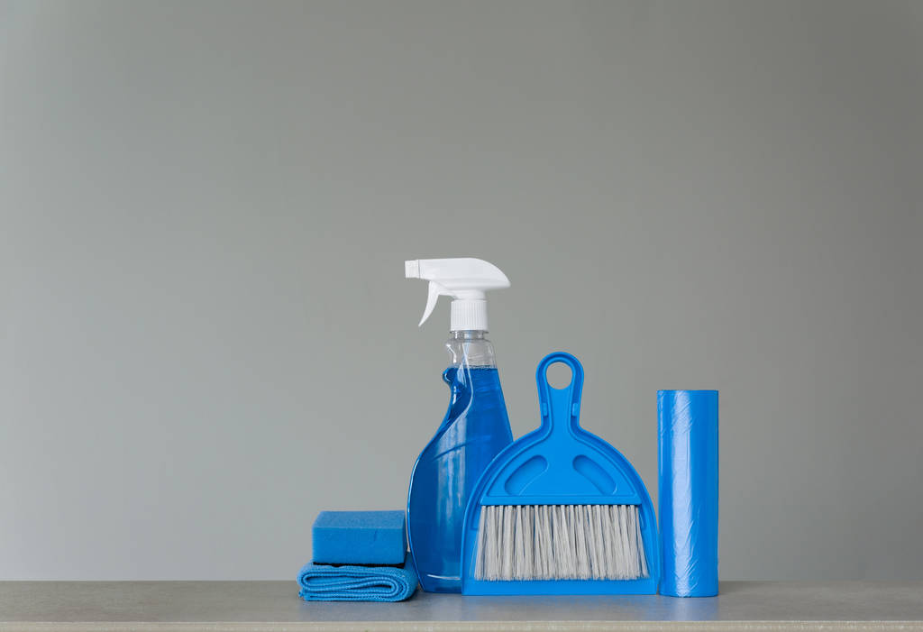 Set di pulizia blu su fondo neutro: detersivo spray, sacchetti della spazzatura, panni antipolvere, spugna, paletta e scopa. Copia spazio
. - Foto, immagini