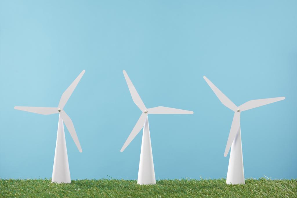 modelos de molino de viento blanco sobre hierba y fondo azul
    - Foto, Imagen