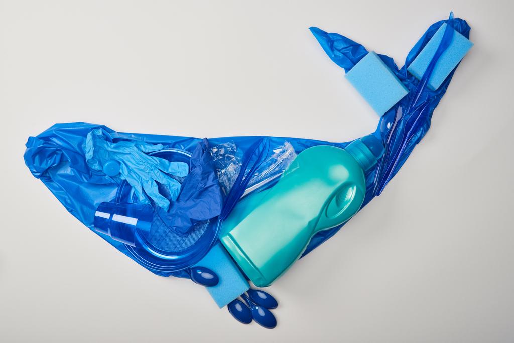 bovenaanzicht van walvis figuur gemaakt van rubberen handschoenen, kunststof platen, bekers, sponzen, lepels, tas en fles geïsoleerd op wit - Foto, afbeelding