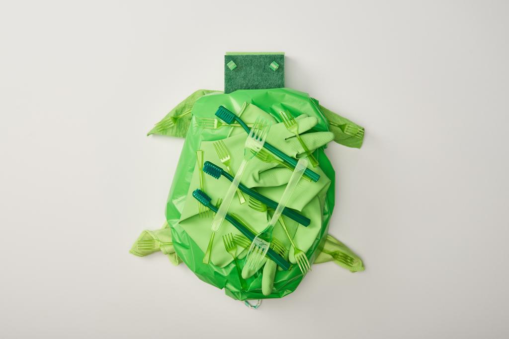 vista superior de la figura de la tortuga hecha de vajilla de plástico desechable, bolso, esponjas y guantes de goma aislados en blanco
 - Foto, Imagen