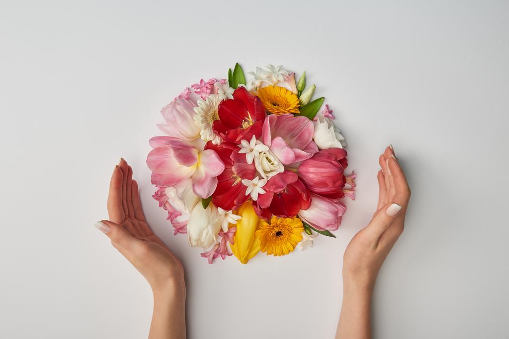 περικοπεί θέα γυναικεία χέρια και μπουκέτο λουλούδια σε λευκό φόντο - Φωτογραφία, εικόνα