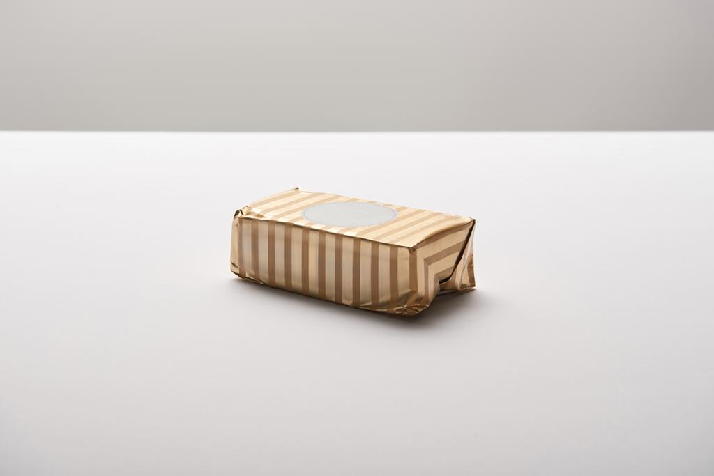 масло в золотой упаковке на белом столе изолированы на сером
  - Фото, изображение