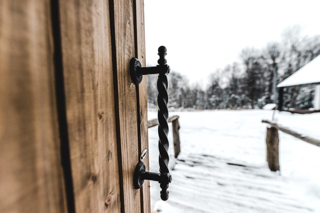 Selektivní fokus otevřené dřevěné dveře s okovaných úchyt a zasněžené krajiny na pozadí  - Fotografie, Obrázek