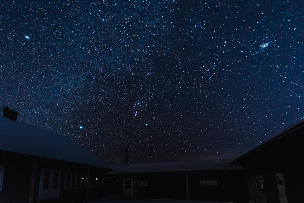 céu escuro estrelado e casas cobertas de neve à noite no inverno
 - Foto, Imagem