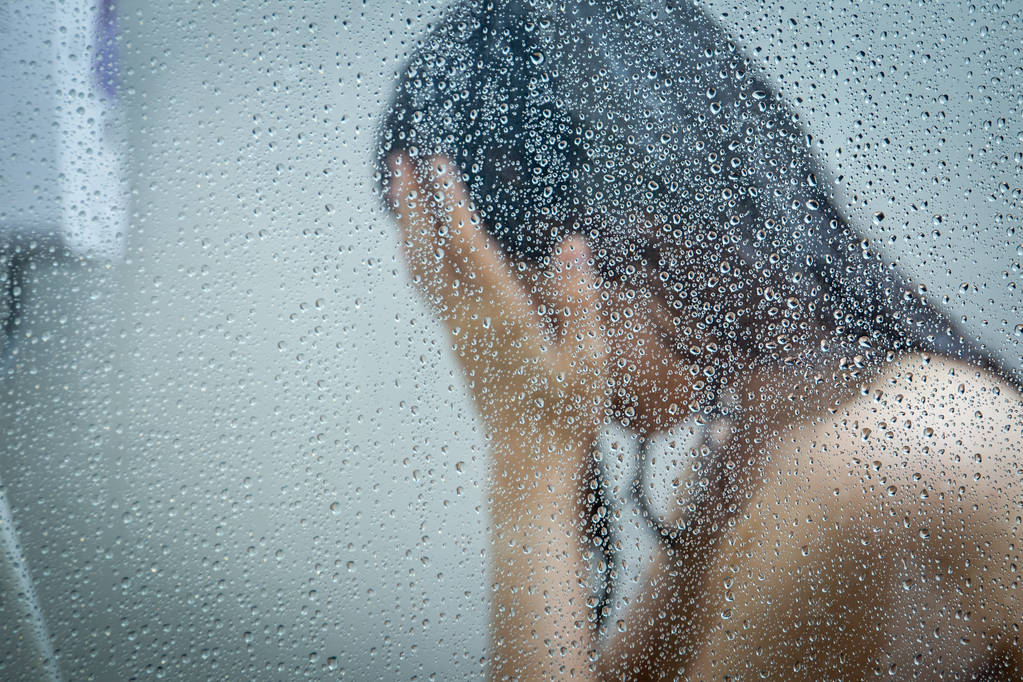 Азійські жінки показують у душовій кімнаті краплі води на склі.. - Фото, зображення
