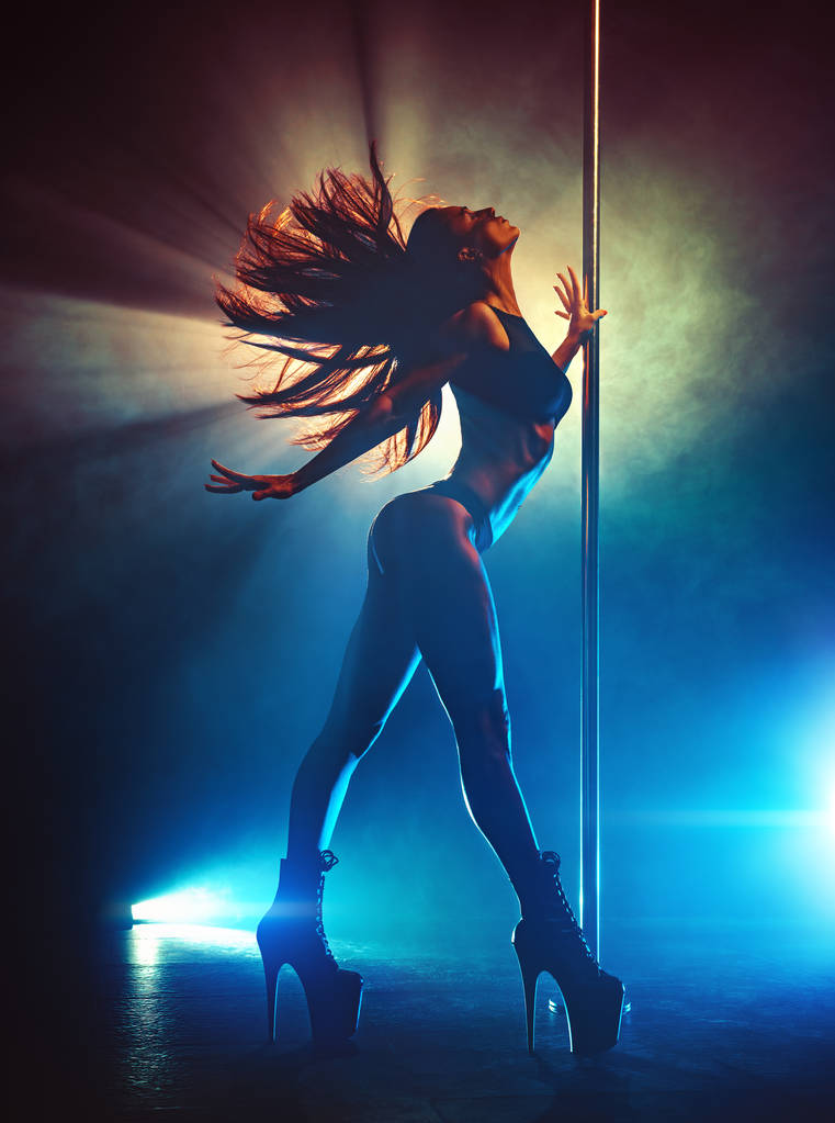 junge sexy schlanke brünette Pole Dance Frau schüttelt die Haare. Silhouette mit Rauch und Licht. - Foto, Bild