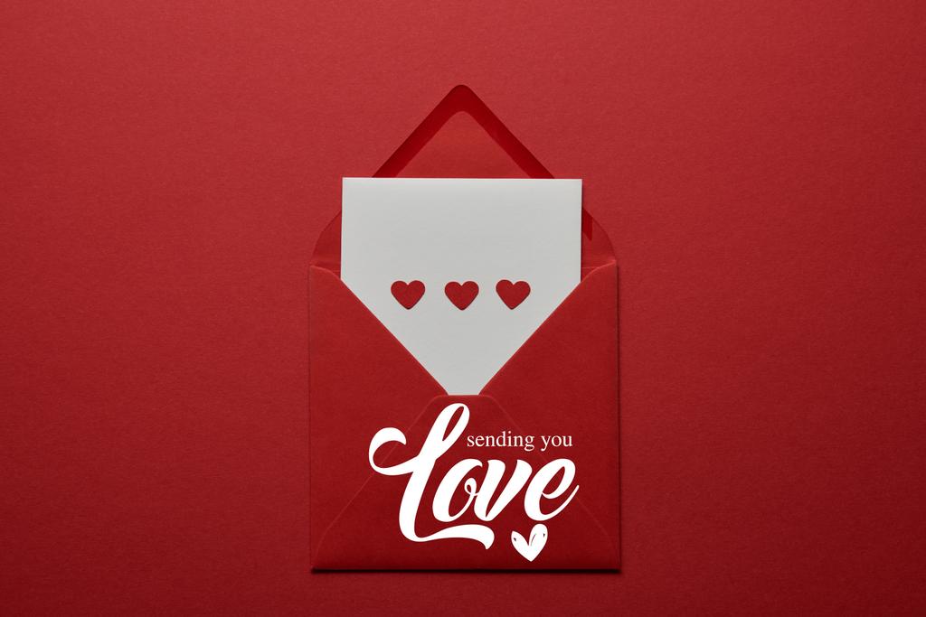 top view of "sending you love" lettering with hearts in envelope on red background - Photo, Image