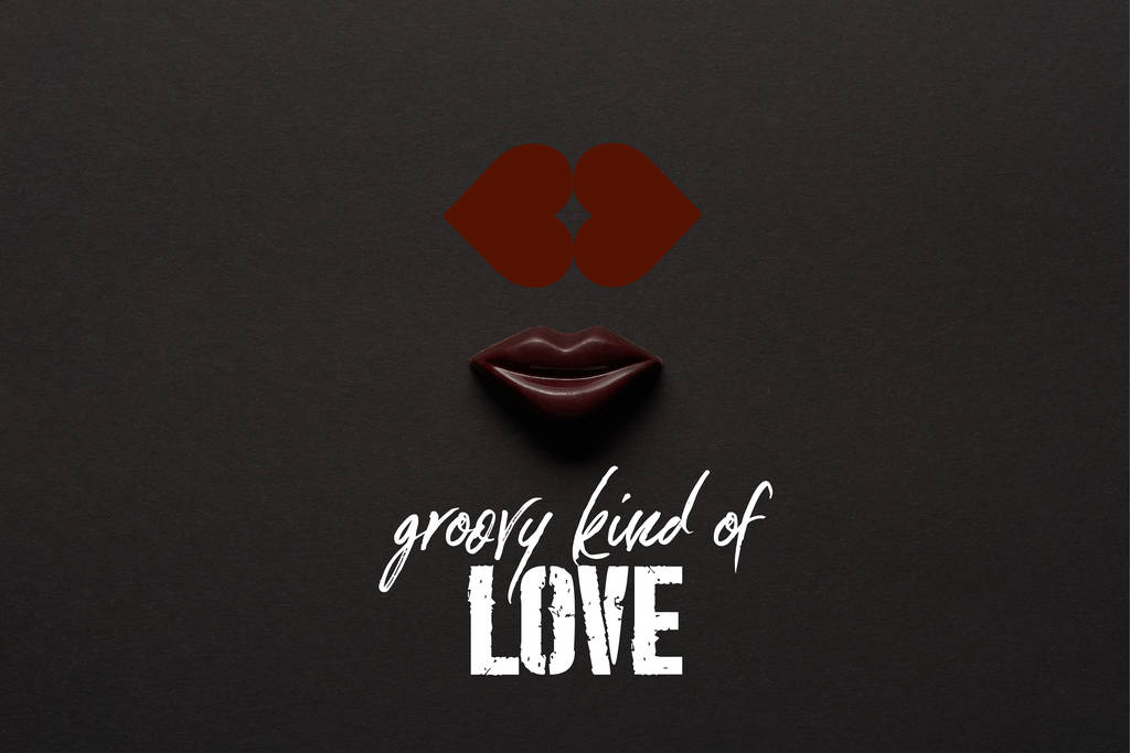 vue du dessus de savoureuses lèvres en chocolat sur fond noir avec lettrage "groovy kind of love"
  - Photo, image
