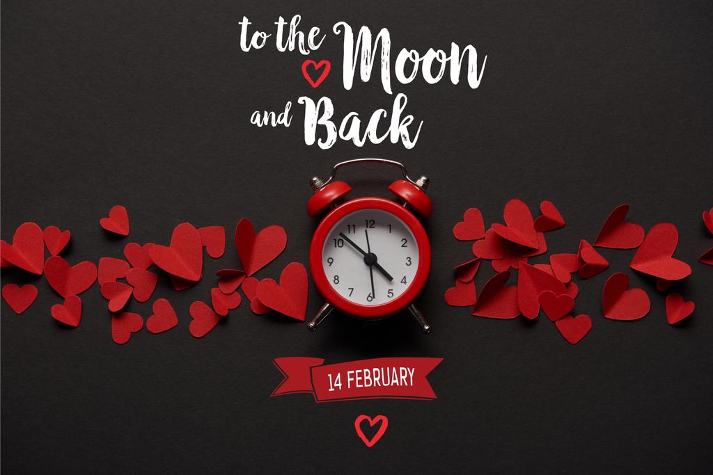 top view of clock and red paper cut decorative hearts on black background with "to the moon and back, 14 february" lettering  - Photo, Image