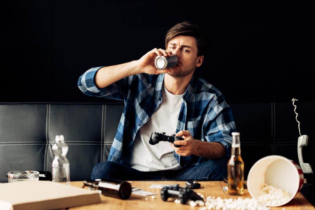 knappe man bier drinken en afspelen van video game thuis - Foto, afbeelding