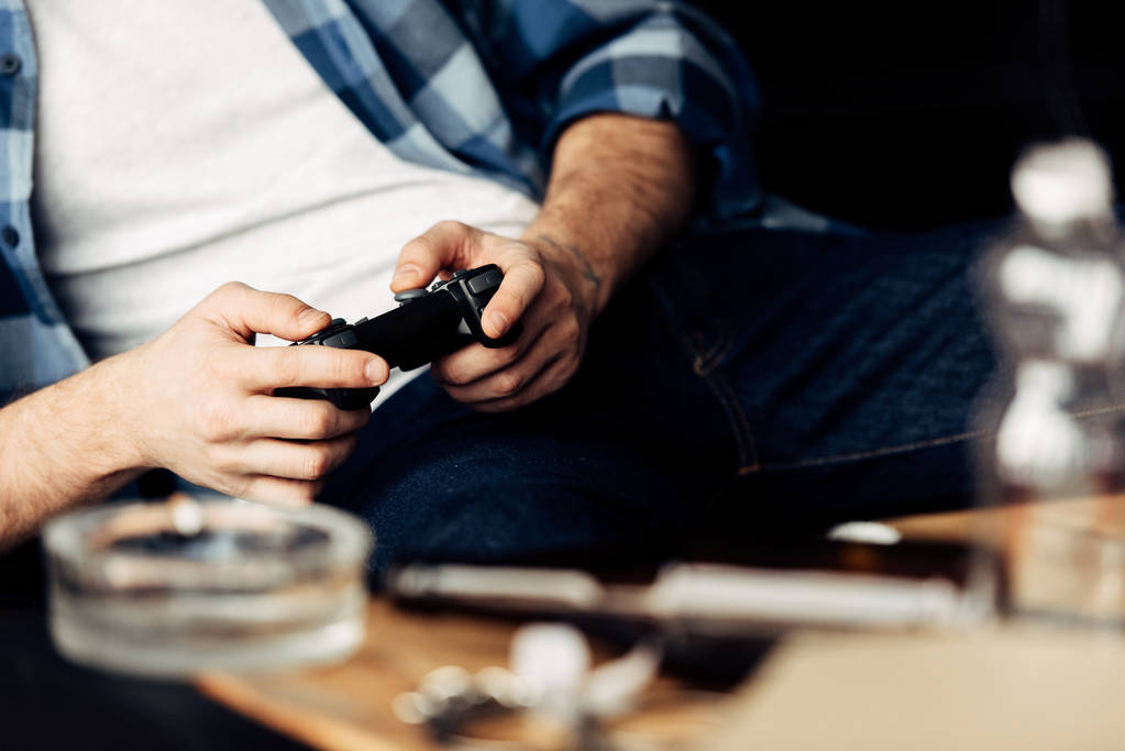 Обрезанный вид человека, играющего в видеоигру дома
  - Фото, изображение