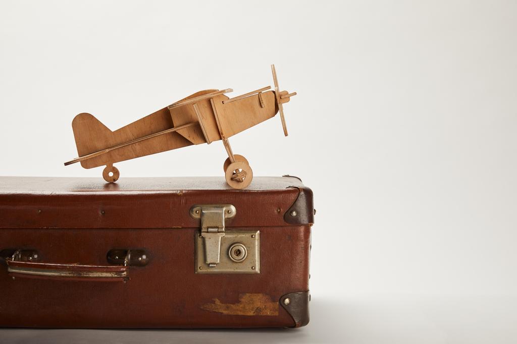 іграшковий літак і шкіряна валіза на сірому фоні з копіювальним простором
  - Фото, зображення