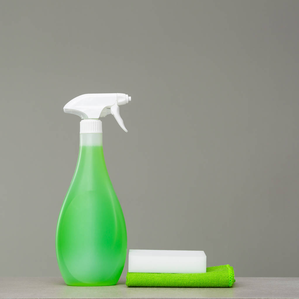 Limpeza frasco de spray verde com dispensador de plástico, esponja e pano para poeira sobre fundo cinza. Ferramentas de limpeza
. - Foto, Imagem