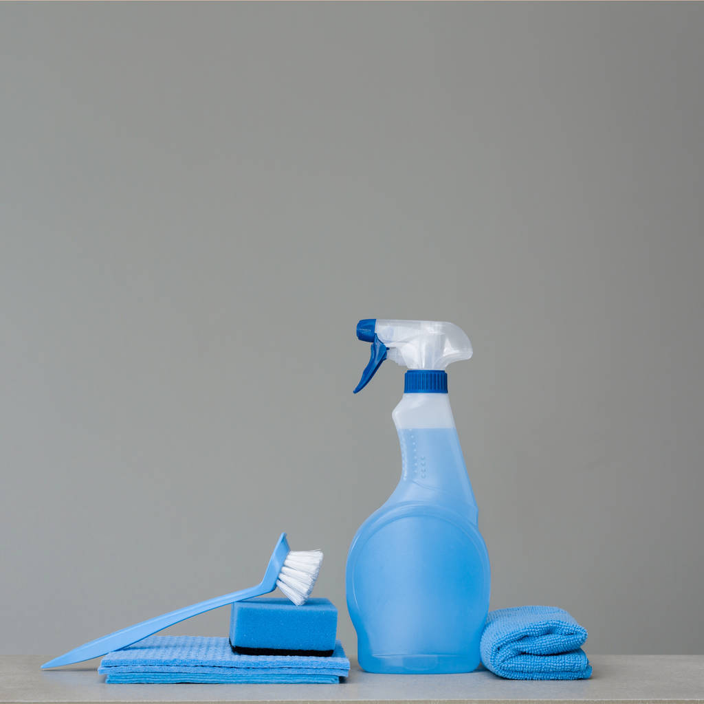 Het reinigen van blauwe sproeiflacon met kunststof dispenser, spons, schrobben borstel voor schotel en doek voor stof op een grijze achtergrond. Het reinigen van gereedschappen. Kopiëren van ruimte. - Foto, afbeelding