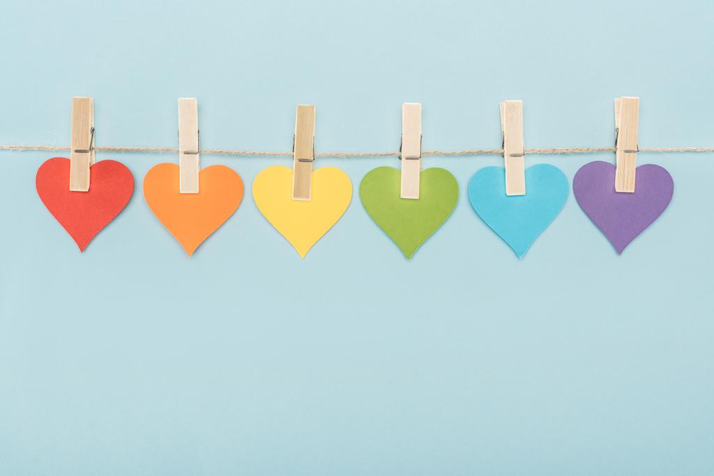 rainbow multicolored paper hearts on rope isolated on blue, lgbt concept - Photo, Image