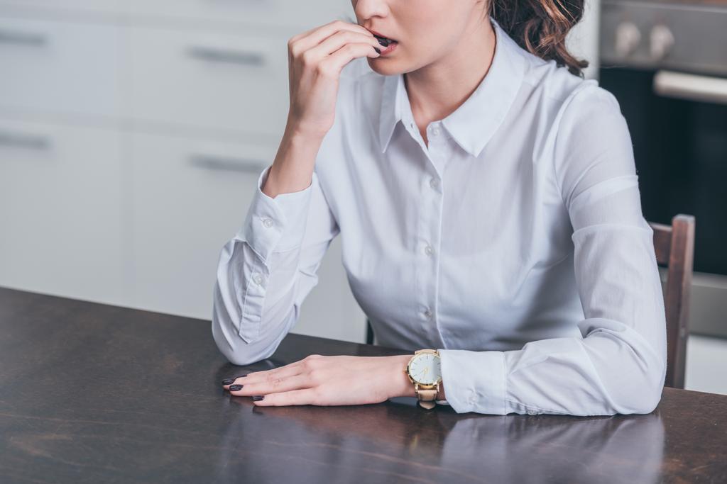 vista cortada de mulher triste em blusa branca sentado à mesa na cozinha, conceito de transtorno de luto
 - Foto, Imagem