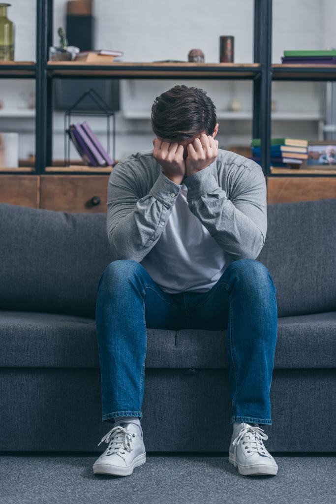 sad man sitting on couch and covering face with hands at home, grieving disorder concept - Photo, Image