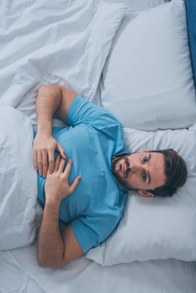 pohled shora smutný osamělý muž ležící v posteli doma - Fotografie, Obrázek