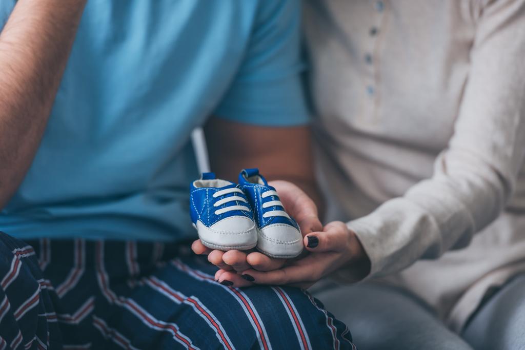 rajattu näkymä vanhempien tilalla vauvan kengät kotona
 - Valokuva, kuva