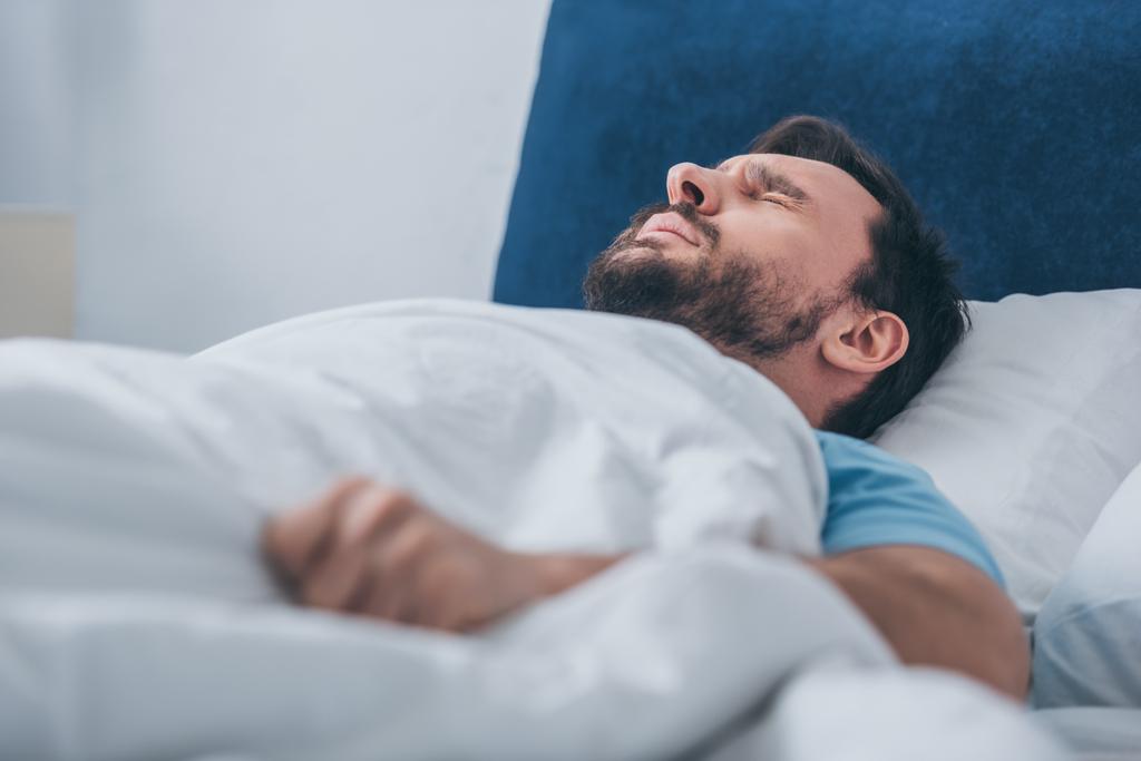 селективное внимание скорбящего мужчины лежащего в постели и держащего одеяло
 - Фото, изображение