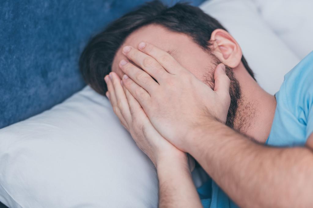 smutný muž v posteli pokrývající obličej rukama a plakat doma - Fotografie, Obrázek