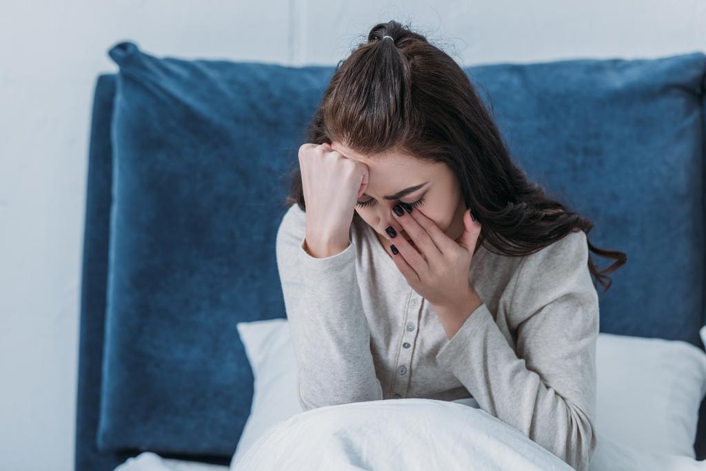 депрессивная женщина плачет и вытирает слезы, лежа в постели дома
 - Фото, изображение