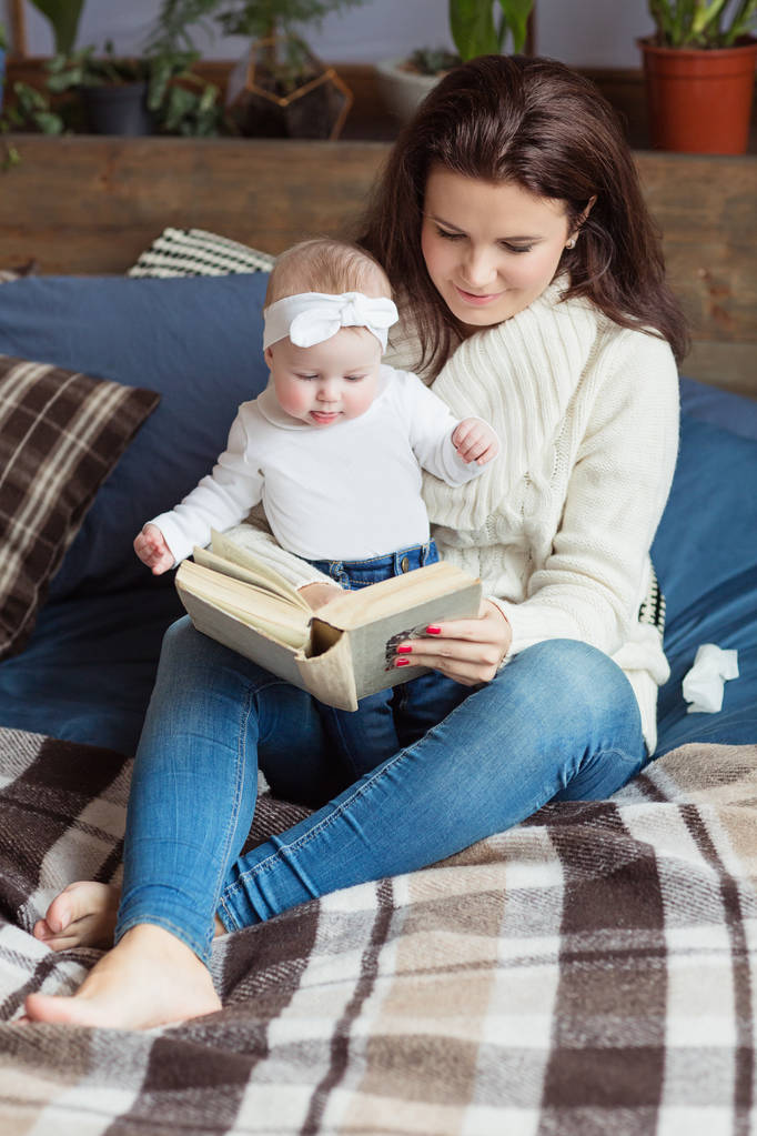 Mutter und kleine Tochter spielen, lesen ein Buch, liegen und entspannen im Bett. Glückliches Familienkonzept - Foto, Bild