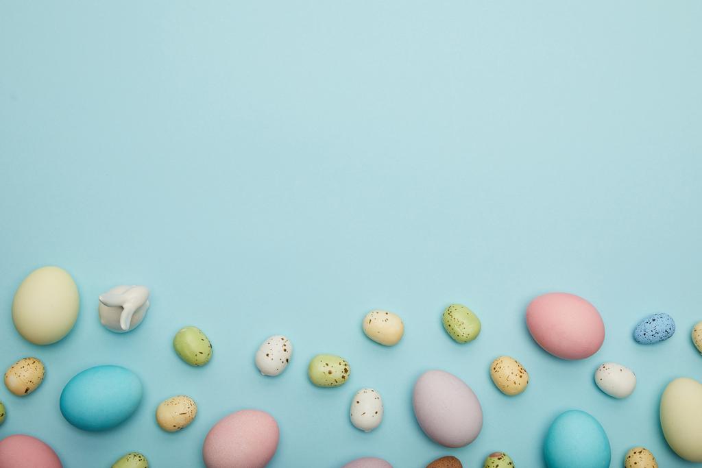 Vista superior del conejito de juguete, pollo de Pascua y huevos de codorniz sobre fondo azul con espacio para hacer frente
  - Foto, imagen