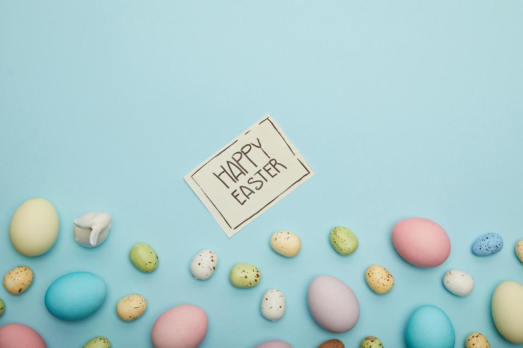 Вид на игрушечного кролика, пасхальные куриные яйца и перепелиные яйца, открытка с радостным пасхальным надписью
 - Фото, изображение