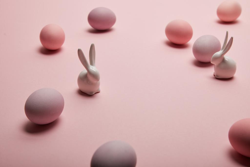 κουνελάκια παιχνίδι και βαμμένα αυγά του Πάσχα σε ροζ φόντο με αντίγραφο χώρου  - Φωτογραφία, εικόνα