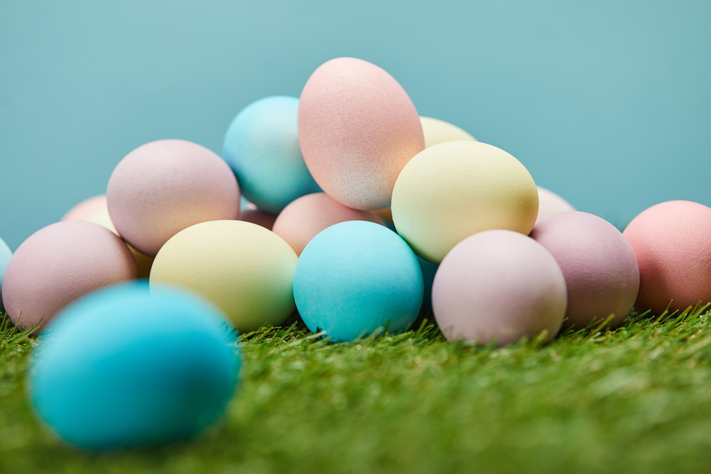 enfoque selectivo de huevos de Pascua pintados sobre hierba y sobre fondo azul
  - Foto, Imagen