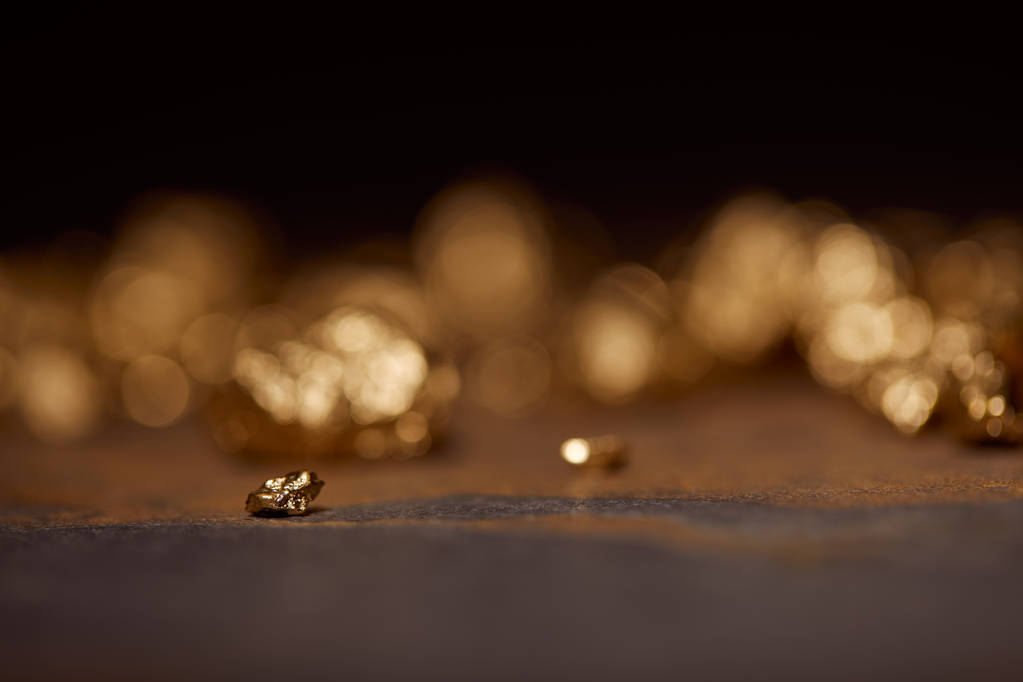 Selektivní fokus malých zlatých kamenů na šedý a hnědý mramor povrch s rozmazané pozadí - Fotografie, Obrázek