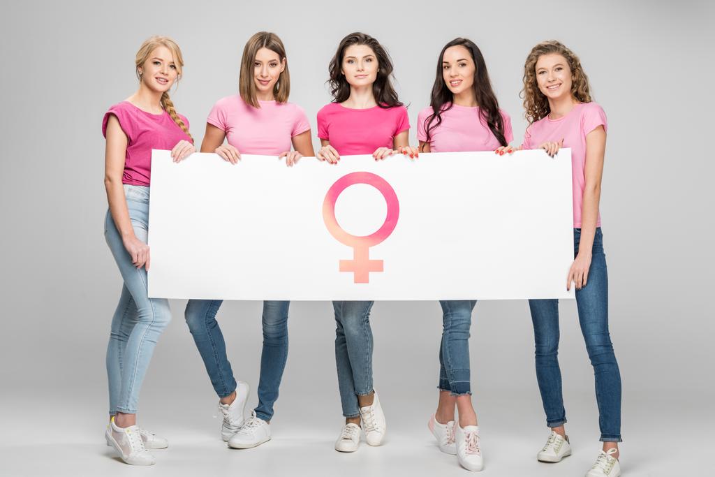 chicas atractivas sosteniendo letrero grande con símbolo femenino sobre fondo gris
 - Foto, imagen